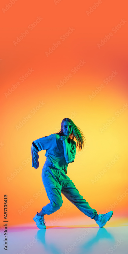 Flyer with young sportive girl dancing hip-hop in stylish clothes on colorful background at dance hall in neon light. Youth culture, movement, style and fashion, action.
