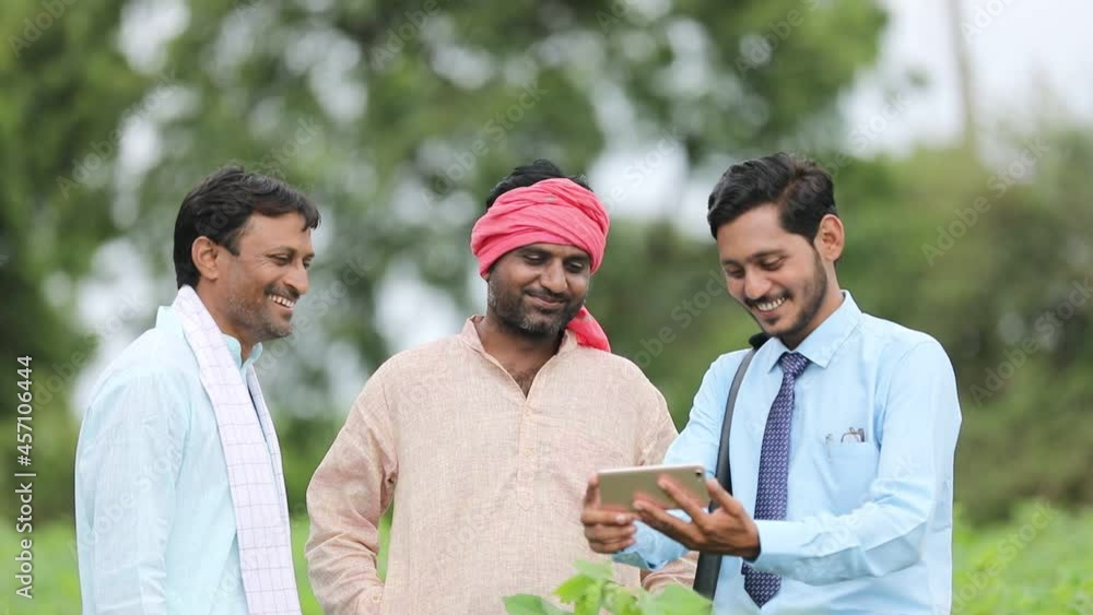 Young indian agronomist or banker showing some information to farmer in smartphone at agriculture field. Young indian agronomist or banker showing some information to farmer in smartphone at agriculture field.
