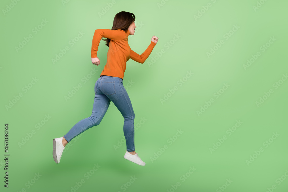 Full length body size profile side view of nice sportive confident girl jumping running sprinter isolated over bright green color background Full length body size profile side view of nice sportive confident girl jumping running sprinter isolated over bright green color background