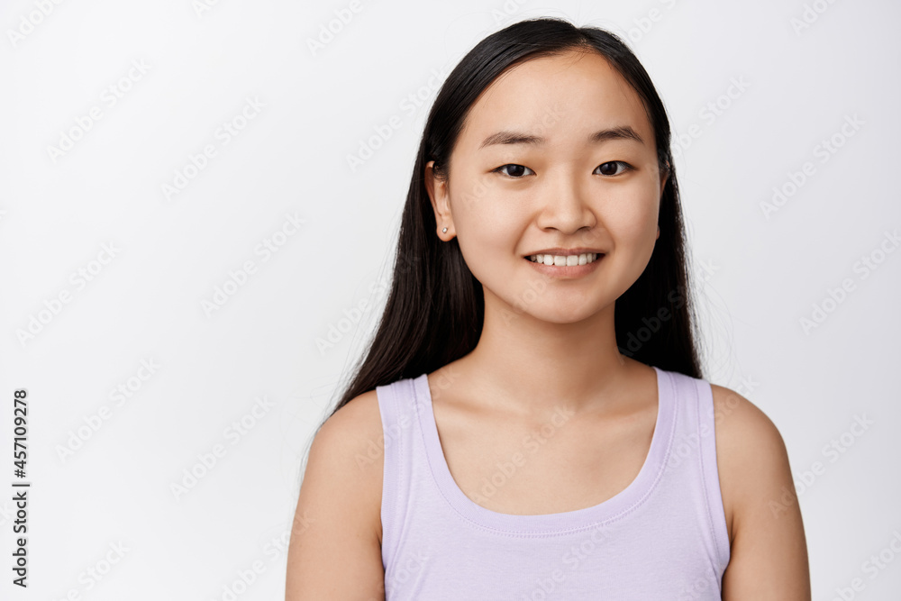 Close up portrait of attractive aisan woman with white smile, looking happy, standing in tank top over white background. Skin care concept Close up portrait of attractive aisan woman with white smile, looking happy, standing in tank top over white background. Skin care concept
