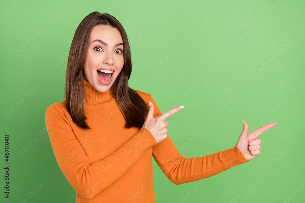 Photo portrait woman smiling amazed overjoyed pointing finger blank space isolated pastel green color background Photo portrait woman smiling amazed overjoyed pointing finger blank space isolated pastel green color background