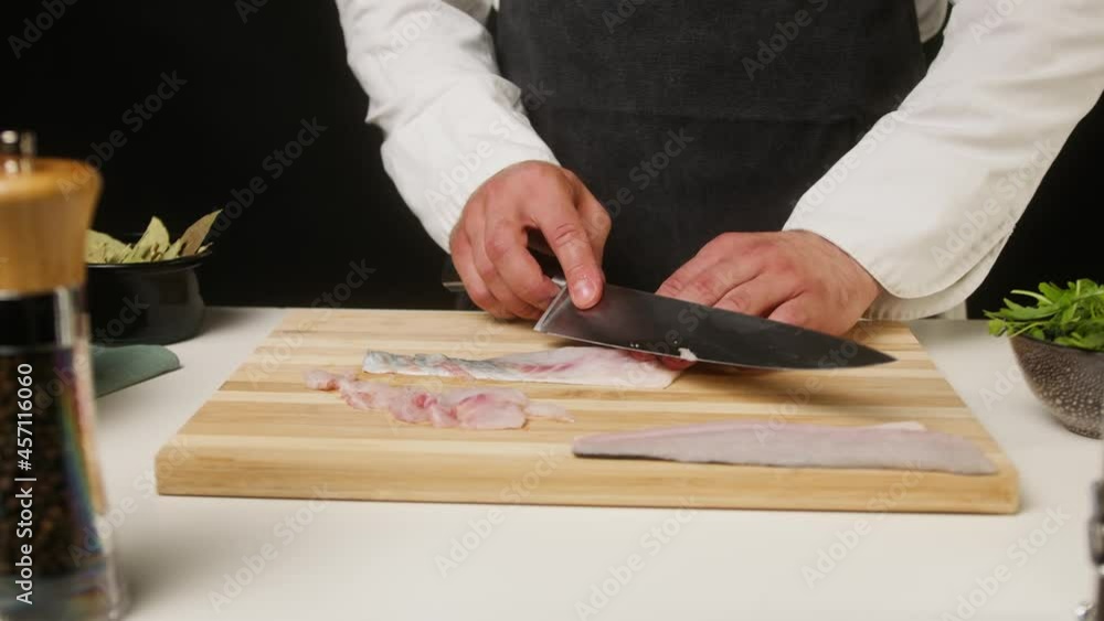 Professional Chef cutting raw white fish close-up, thin slices. Man cooking seafood dishes using sharp knife, wearing apron. Process of preparing ingredients for Peruvian ceviche. Professional Chef cutting raw white fish close-up, thin slices. Man cooking seafood dishes using sharp knife, wearing apron. Process of preparing ingredients for Peruvian ceviche.