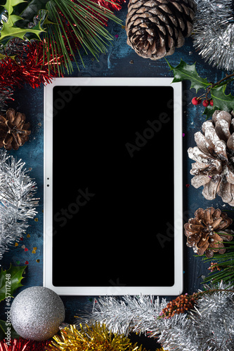 tableta digital blanca con pantalla vacía rodeada por adornos navideños photo