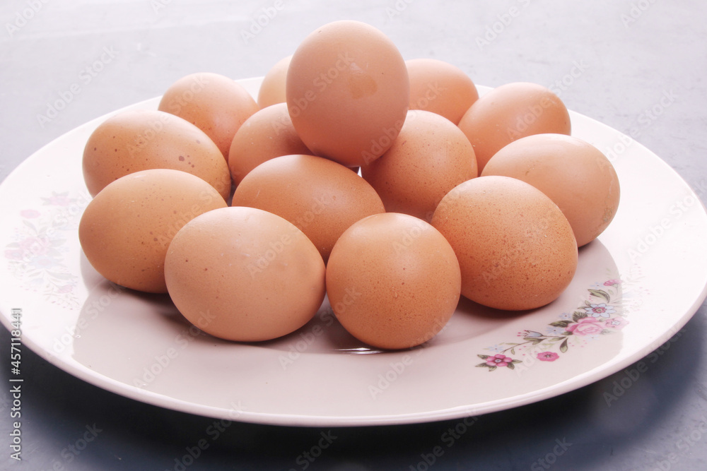 Randomly stacked pile of raw chicken eggs on a white plate Randomly stacked pile of raw chicken eggs on a white plate