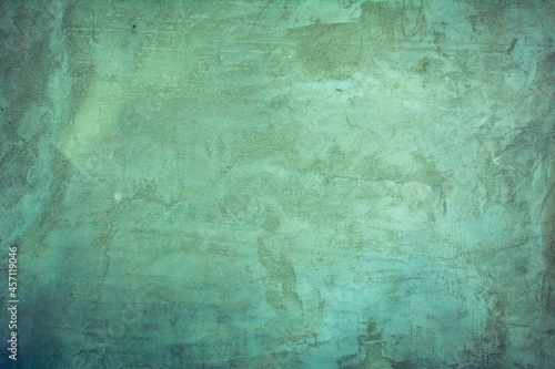 Old green wall in spots, cracks, stains. Painted concrete wall in abstract grunge style loft. Vintage wall background texture for backgrounds, portraits, posters. © Ponomus