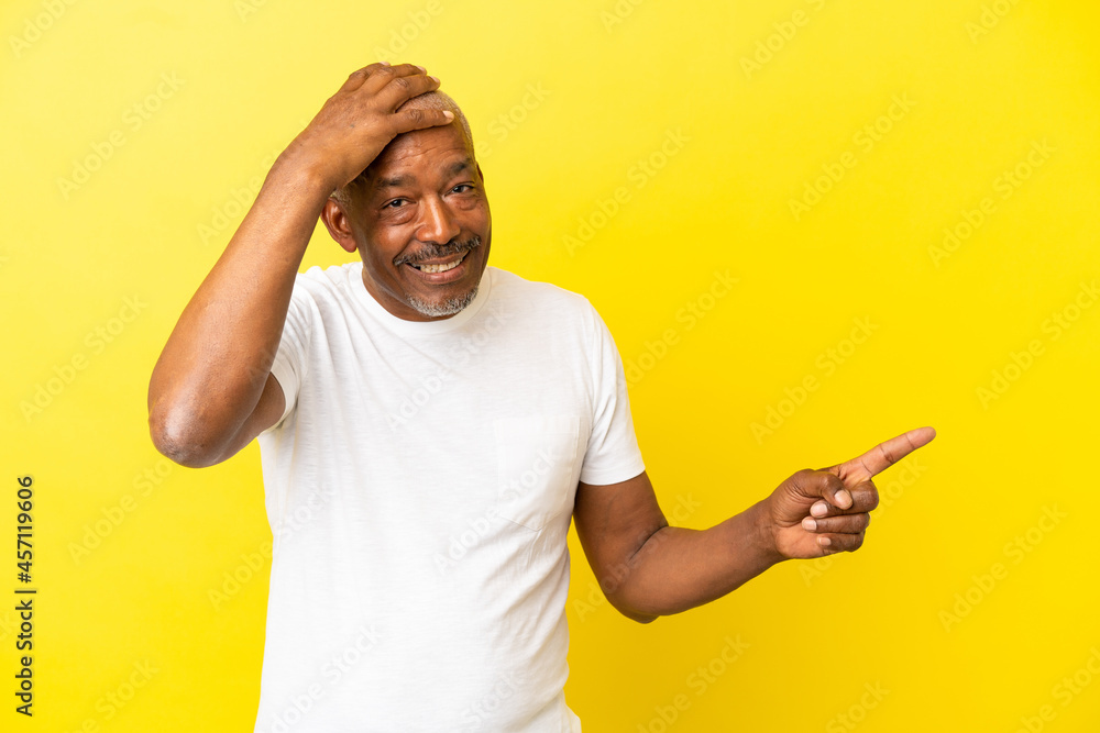 Cuban Senior isolated on yellow background surprised and pointing finger to the side Cuban Senior isolated on yellow background surprised and pointing finger to the side
