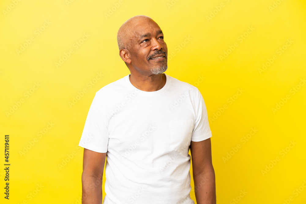 Cuban Senior isolated on yellow background looking to the side and smiling Cuban Senior isolated on yellow background looking to the side and smiling