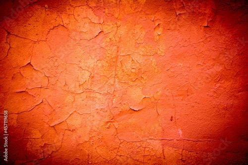 Old orange wall in spots, cracks, stains. Painted concrete wall in abstract grunge style loft. Vintage wall background texture for backgrounds, portraits, posters.
