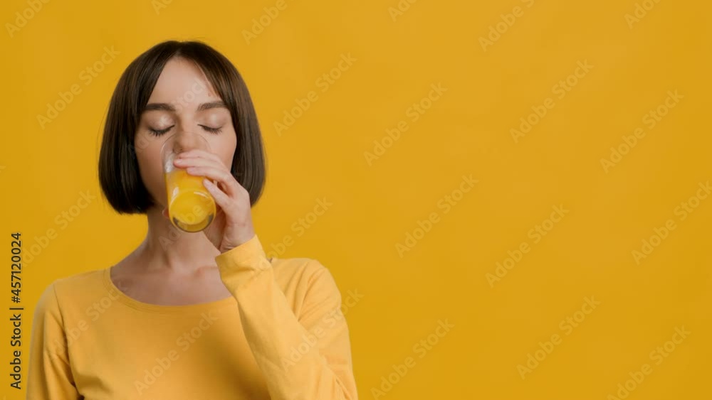 Cheerful Woman Drinking Glass Of Orange Juice Over Yellow Background Cheerful Woman Drinking Glass Of Orange Juice Over Yellow Background