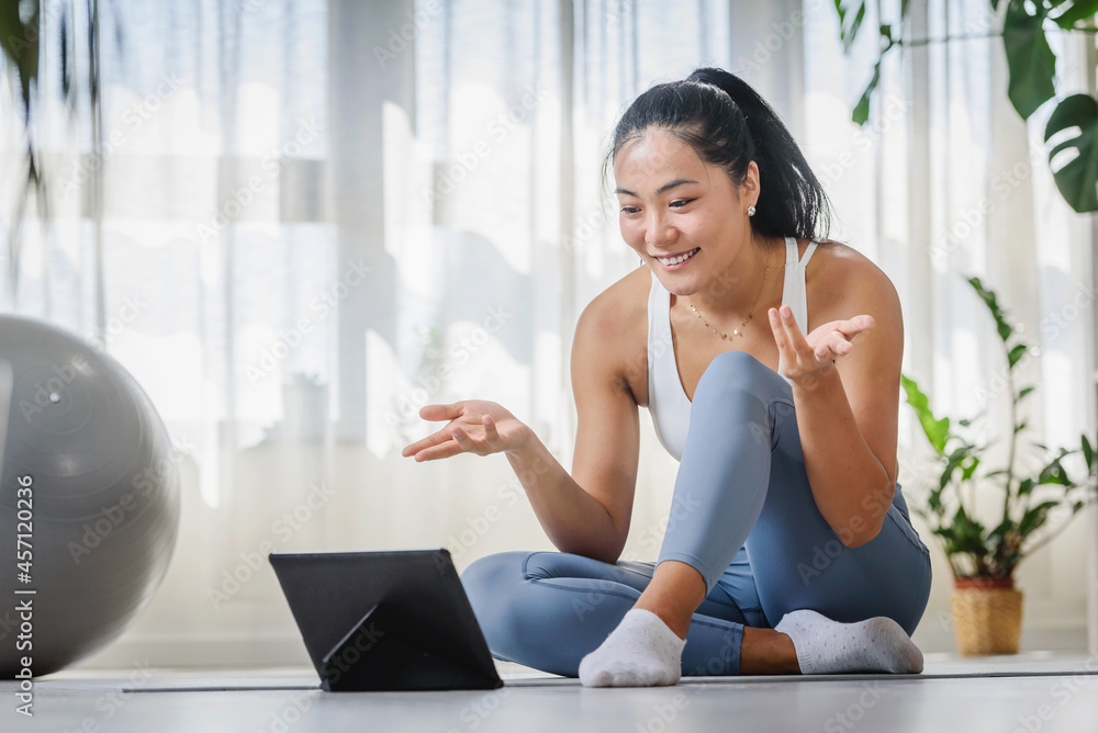Young Asian woman yoga instructor using tablet on an online yoga class Young Asian woman yoga instructor using tablet on an online yoga class