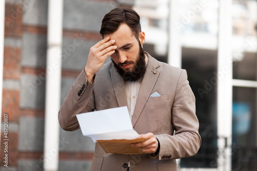 The guy is upset by the statistics of profit growth in his company. The man has a.headache because of work. Businessmen read documents. photo