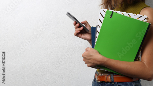 Closeup of woman who holding noteboks and smarthone against white empty background photo