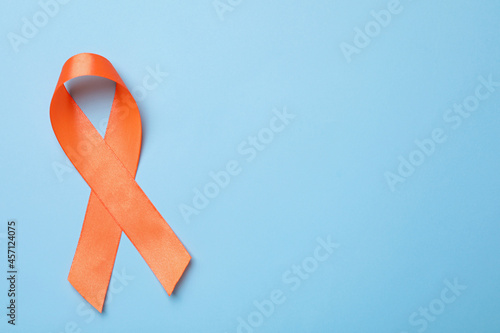 Orange ribbon on light blue background, top view with space for text. Multiple sclerosis awareness photo