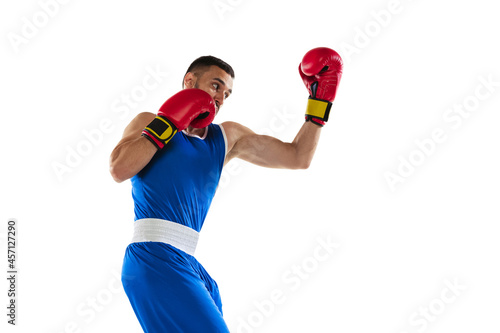 Portrait of one professional boxer in blue uniform training isolated over white background. Uppercut punch photo