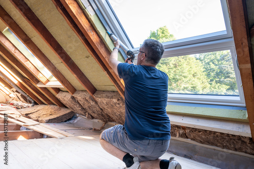 Craftsman caulking a new window in the attic. photo