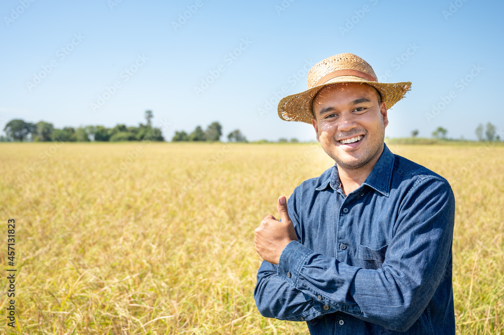 Owner farmer with a hat smile and show thumb up at his rice field. Concept of agricultural business.