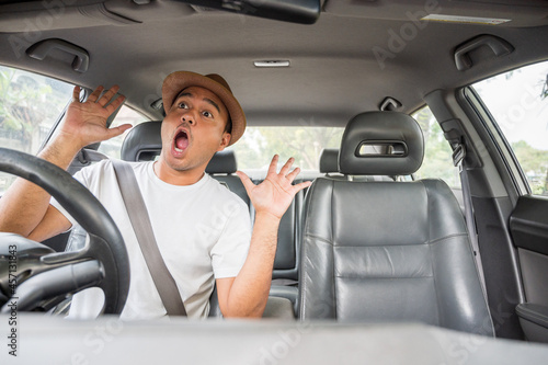 Handsome asian man with hat look outside shocked and surprised  looking in his car.