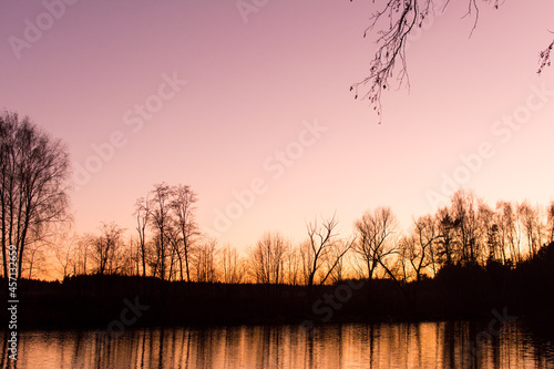 Beautiful autumn natural park with a river, trees at sunset.