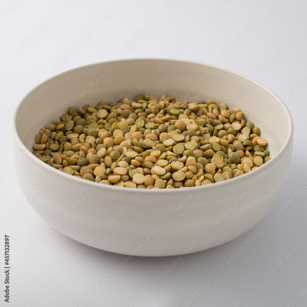 White round plate full of uncooked green lentils. isolated on white White round plate full of uncooked green lentils. isolated on white