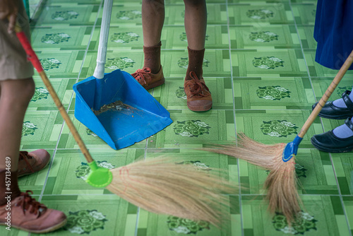 Surin, THAILAND - October 12, 2020:Three Thai young students in school uniforms are sweeping and cleaning the corridor of the School building floor. in their school every morning.