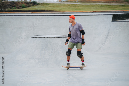 Mature skater in a watch cap riding on a skateboard in a skate park
