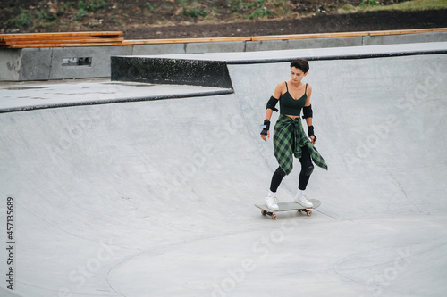 Longshot of a woman skater riding on her board on quarter pipe circle
