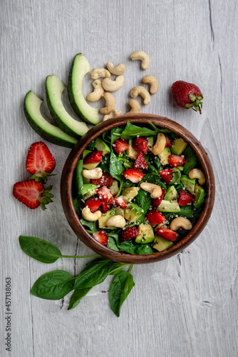 Fototapeta Naklejka Na Ścianę i Meble -  Healthy veggie salad with avocado, arugula, spinach, strawberries, cashews and seeds- low carbohydrate, low calorie diet. Healthy eating, nutrition and diet concept. Top view, flat lay