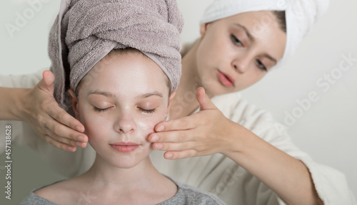 Two girls playing with cosmetic SPA mask on their faces. Little girl and young woman enjoy spa treatments. SPA and wellness