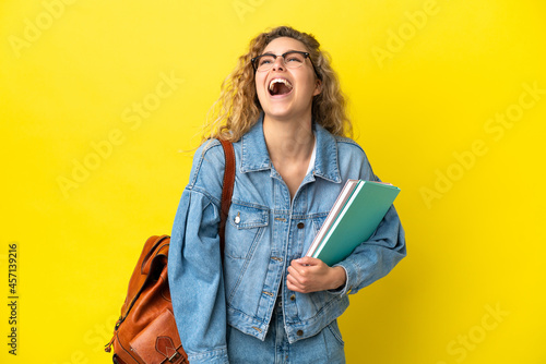 Young student caucasian woman isolated on yellow background laughing