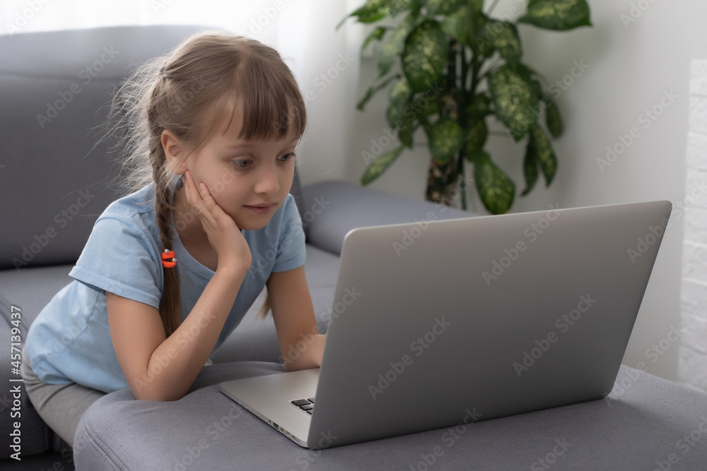 Bored little girl with laptop at home. Cute child doing homework on computer. Modern online education, communication and technology concept, copy space. Bored little girl with laptop at home. Cute child doing homework on computer. Modern online education, communication and technology concept, copy space.