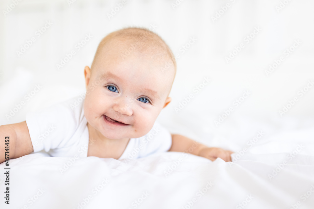 Portrait of cute and smiling four month old baby girl playing on the bed in her room. Happy and dry kid. Portrait of cute and smiling four month old baby girl playing on the bed in her room. Happy and dry kid.