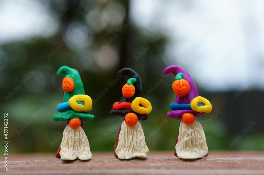 Figures of three dwarfs made of plasticine, decorated with a festive hat and a pumpkin. The concept of Halloween.
