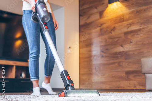oman cleaning floor and carpet with cordless vacuum cleaner at home. photo