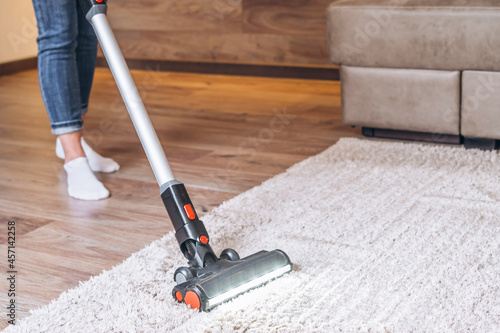 oman cleaning floor and carpet with cordless vacuum cleaner at home.