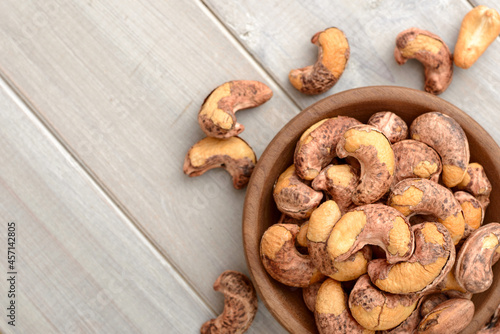 roasted cashew nuts in the wooden bowl on the table, top view