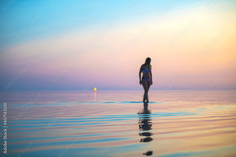 a girl on the seashore at sunset walks on the water