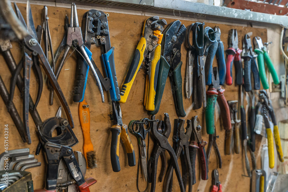 Set of pliers and nippers tools hanging on a wall Set of pliers and nippers tools hanging on a wall