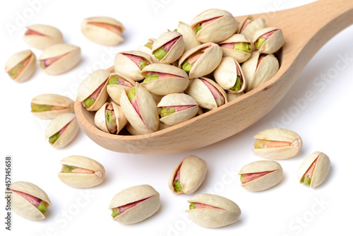 pistachio nuts with shell in the wooden spoon, isolated on the white background