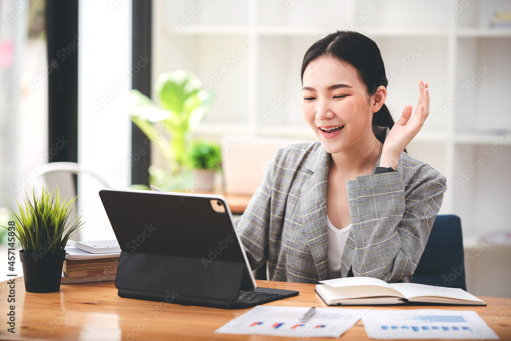 Asian girls are enjoying business video call, sitting at desk, using laptop computer, having video chat, waving Asian girls are enjoying business video call, sitting at desk, using laptop computer, having video chat, waving