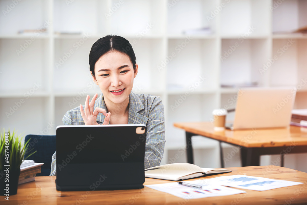 Asian girls are enjoying business video call, sitting at desk, using laptop computer, having video chat, waving Asian girls are enjoying business video call, sitting at desk, using laptop computer, having video chat, waving