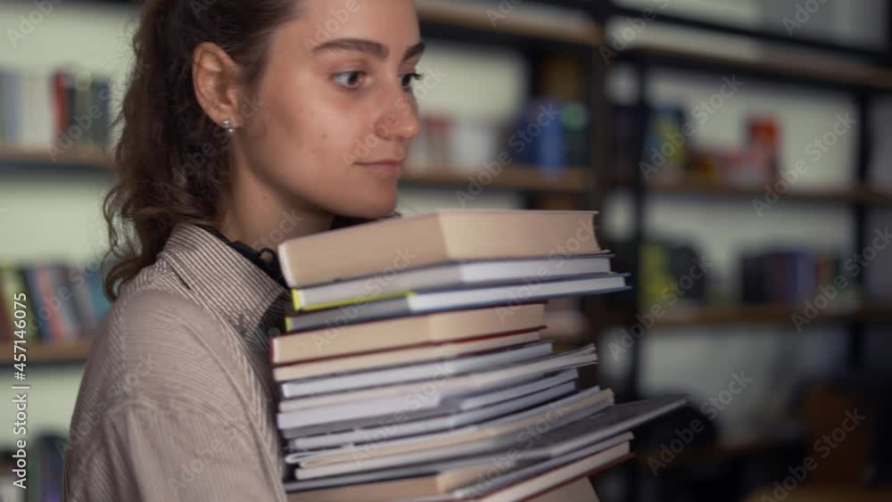 Girl student holding a lot of books in the library, preparing for exams Girl student holding a lot of books in the library, preparing for exams