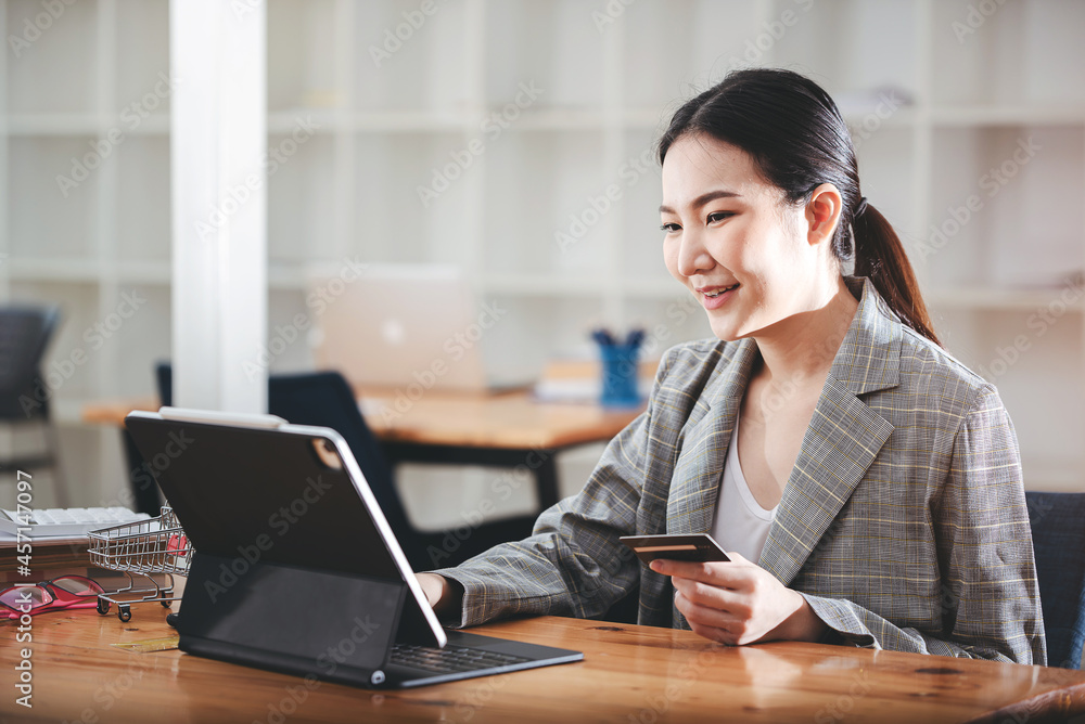 girl holding a credit card and using a laptop Business woman working from home . online shopping, ecommerce, internet banking, spend money, work from home concept. girl holding a credit card and using a laptop Business woman working from home . online shopping, ecommerce, internet banking, spend money, work from home concept.