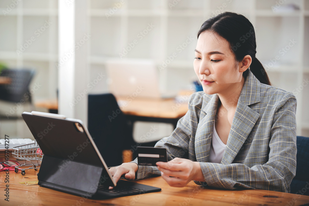 girl holding a credit card and using a laptop Business woman working from home . online shopping, ecommerce, internet banking, spend money, work from home concept. girl holding a credit card and using a laptop Business woman working from home . online shopping, ecommerce, internet banking, spend money, work from home concept.