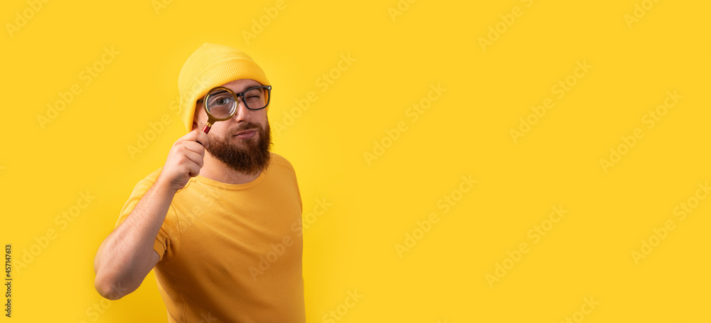 man looking through magnifying glass over yellow background, searching concept, panoramic image