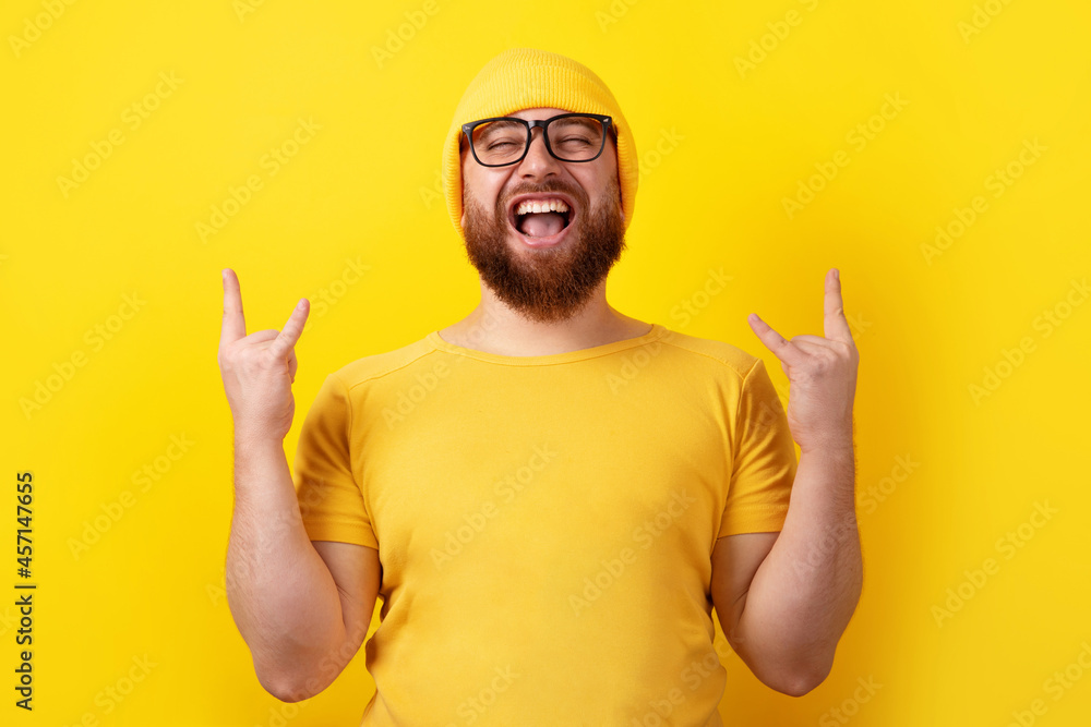 positive man makes rock n roll gesture over yellow background, people and body language concept positive man makes rock n roll gesture over yellow background, people and body language concept