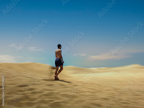 Hombre caminando por dunas en movimiento, islas canarias © Manuel