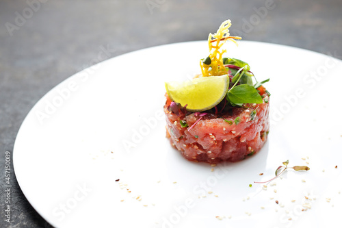 Foto A horizontal view of a salmon tartar on an elegant white plate, on a black stony background