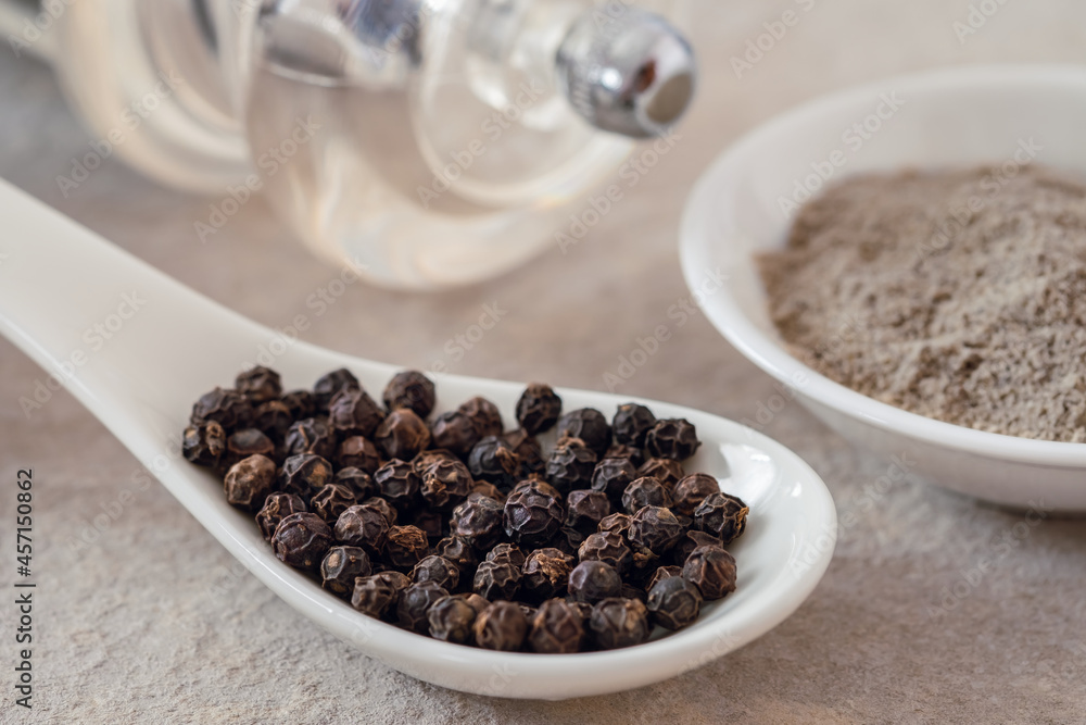 Black pepper corn on spoon and black pepper powder in bowl. Black pepper corn on spoon and black pepper powder in bowl.