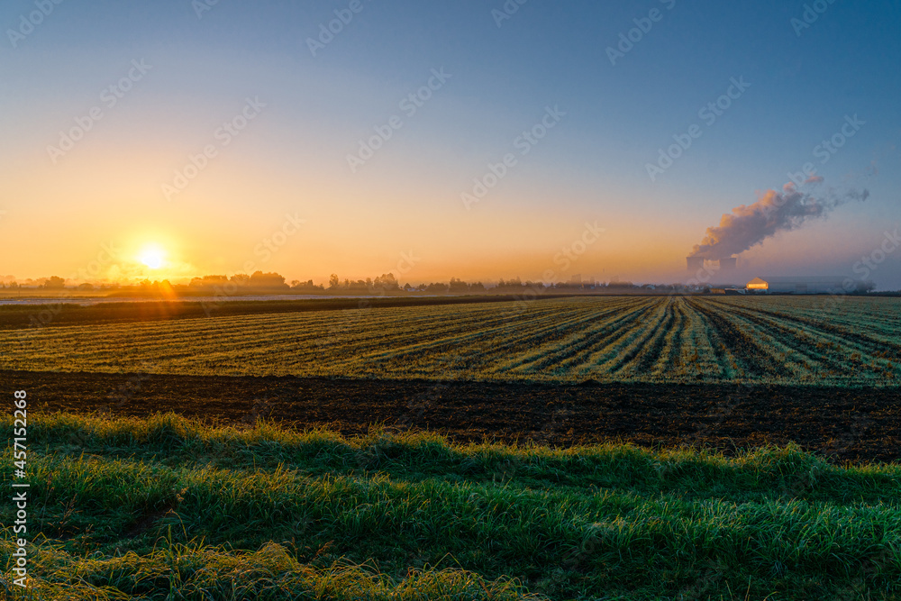 Sonnenaufgang am Atomkraftwerk Gundremmingen, Blick auf Felder, Kühltürme und Dampfwolke im Morgenlicht