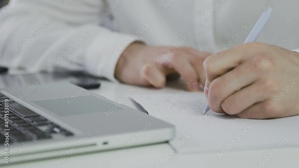 An unrecognizable man makes notes on paper. Remote work. Freelance. Video in motion. Close-up An unrecognizable man makes notes on paper. Remote work. Freelance. Video in motion. Close-up